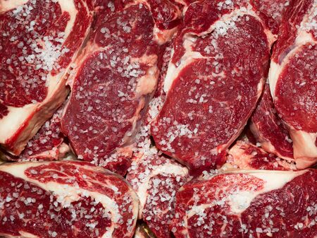 Fresh raw beef steak with salt on wooden cutting board, top viewの写真素材