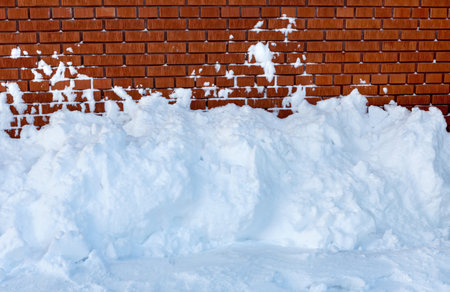 Snow snowdrift against a brick wall. Snow removal.の写真素材