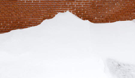 Snow snowdrift against a brick wall.の写真素材