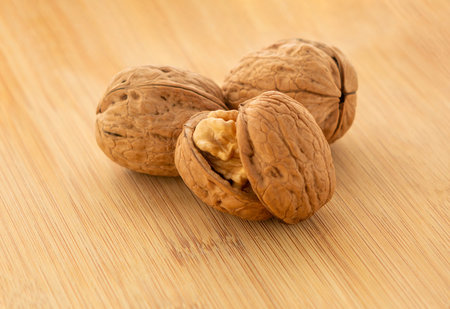 Walnut kernels and whole walnuts on wooden table, close-up.