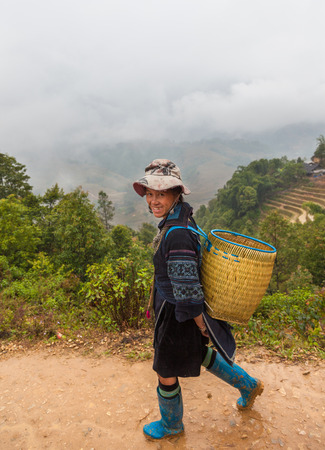 Sa pa, Vietnam-December 13, 2013. BLack Hmong woman carrying traditional basket on the shoulders walks home from Sa pa town to village in Muong Hoa Valley on December 13, 2013 in North Vietnam.のeditorial素材