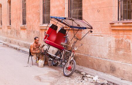 Havana, Cuba-October 07, 2016. Unindentified cuban man repaires his threecycle, used as transportaition for tourist, on October 07 2016 at street of old part of Havana City.のeditorial素材