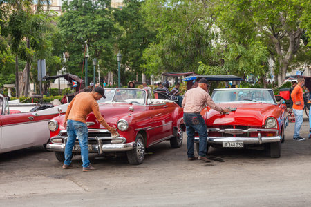 Havana, Cuba-October 07, 2016. Two driver are cleaning and preparing for tourist their classic, old...