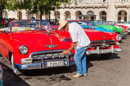 Havana, Cuba-October 08, 2016. Driver looks after his classic, old style, American car and waiting for passengers on October 08, 2016 at old part of Havana City in Cuba.のeditorial素材