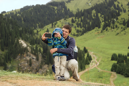 father and son taking selfie while hinking in mountains, family travelの写真素材