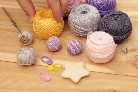Colorful yarn, fingers and crochet hook on wooden backgroundの写真素材