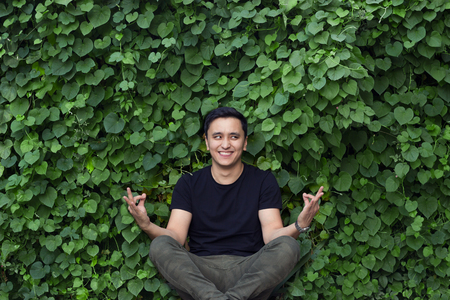 smiling asian young man in black t-shirt posing yogaの写真素材