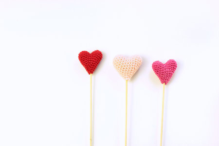 Saint Valentine concept. Three knitted heart on white background.