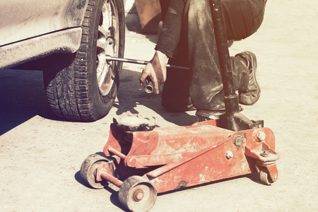 Rust and mud scene of wheel perair process whith red hydraulic floor jack life styleの写真素材