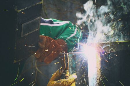 Close up view on man with weld mask during weld work with sparks all aroundの写真素材