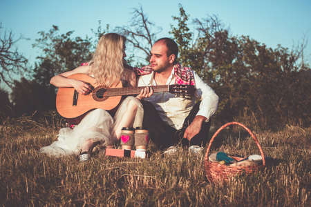 Little family romantic picnic scene outdoor in sunset. Parents holding hands and little toddler boy playing near them.の写真素材