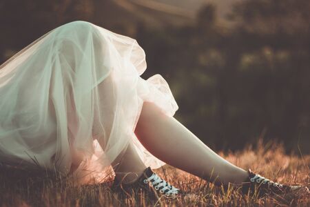 Close up view on attractive young woman legs in converse shoes and white tulle skirt in sunset light outdoor.の写真素材