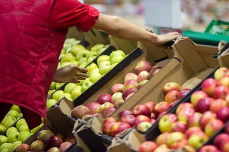 Young man seller lays out fresh fruits of the box on the grocery storeの写真素材