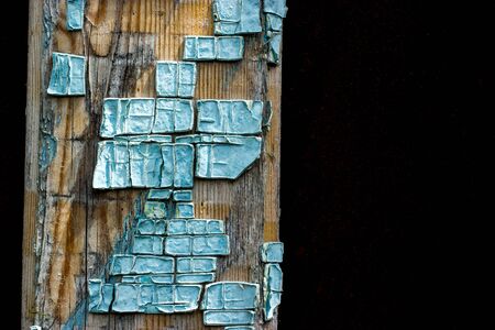 Part of old wooden boards painted in light blue cracked paint with several layers of shelled paint piecesの写真素材