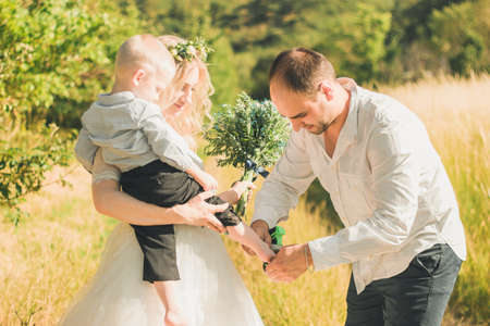 Happy family with kid walking together in wheat field on warm and sunny summer day. Soft focus.の写真素材