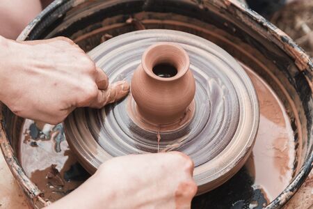 A close up view on ceramic production process on potter's wheel with children. Clay crafts with kids concept.の写真素材