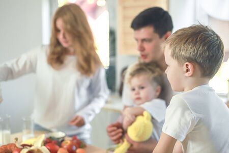 Happy family mother, father, child daughter and son having breakfast at home. Vitamine breakfast in bright kitchen room interior. Blur background.の写真素材