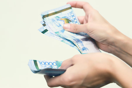 The women hand holds the national currency of Kazakhstan tenge.