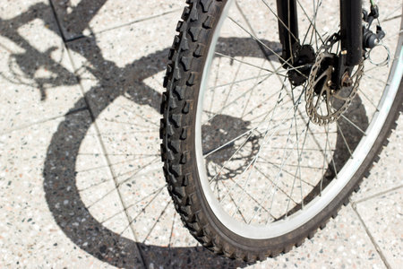 Bycycle front wheel tire and shadow silhouette on urban concrete tile surface