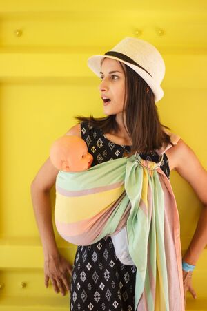 Almaty, Kazakhstan - July 08, 2019: Young beautiful babywearing mother carry her newborn baby in a ring sling in an urban scene.のeditorial素材