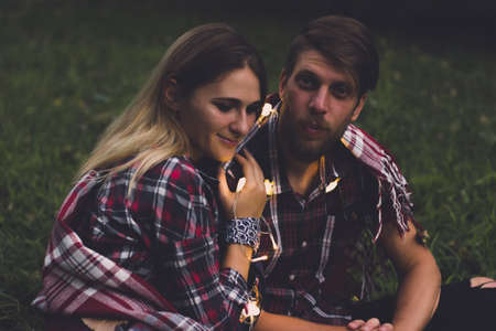 A young couple of lovers missed the train. Playing song with guitar on the rails in the autumn forest waiting for the next train.の写真素材