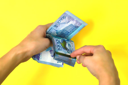 A stack of banknotes of ten thousand tenge. Yellow background.