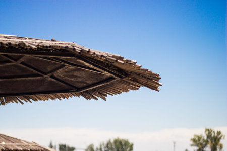 Wicker roof beach umbrella and blue sky. Beach island by sea. Natural bamboo sunshades and summer...