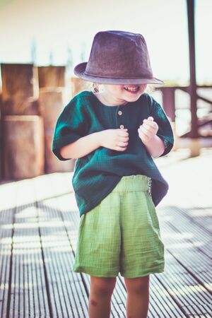 Portrait of happy cute emotional little girl in rural style brown hat and muslin clothes in a summer day.の写真素材