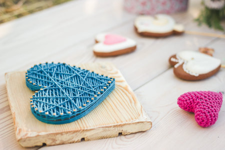 Close up view on string art and crochet heart shaped wedding decor. Heart shaped cookies on a stick