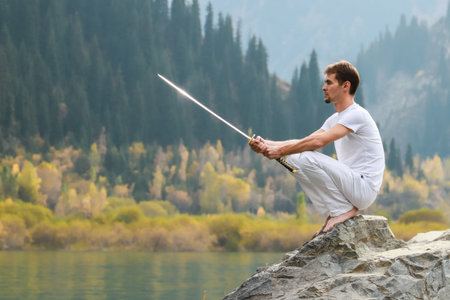 A wise man sits on a stone and holds a sword in his hands.