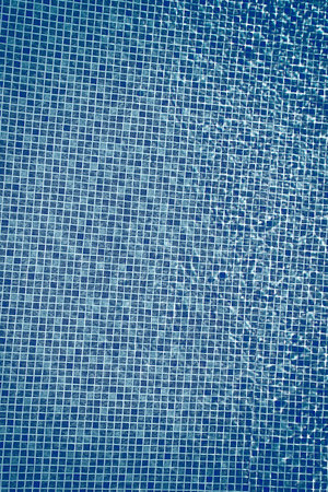 Top view of clear water in a blue tile pool background. Ripple effect