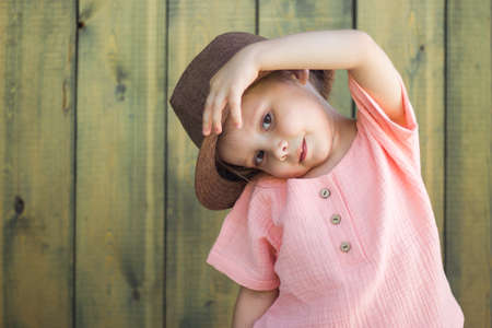 Close up portrait of happy cute little girl in rural style brown hat in a summer day.の写真素材