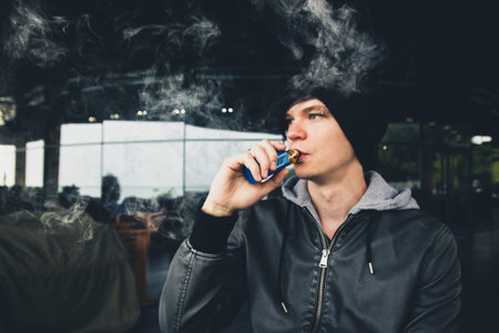 Vape steamer urban youngster casual look in outdoor cafe
