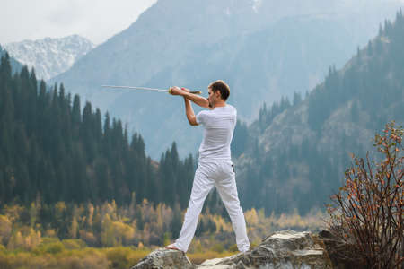 A man holds a Japanese sword katana above his head. Training combat skills.の写真素材
