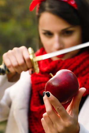 A woman with a sharp blade in her hands is about to cut a red apple.の写真素材