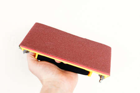The yellow sandpaper holder in hand on white background.の写真素材