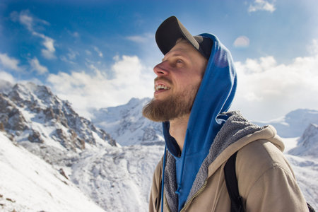 A bearded guy among snow mountains rejoices in life