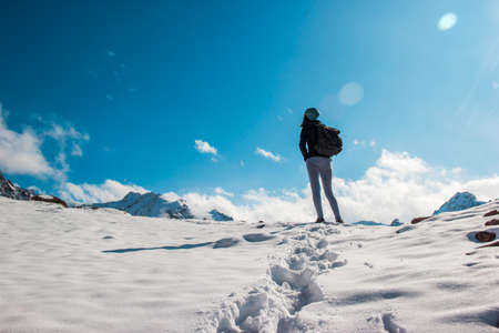 A young woman on a snow top amid a blue sky. White cloudsの写真素材