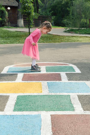 Young cute girl playing hopscotch on backyard.の写真素材