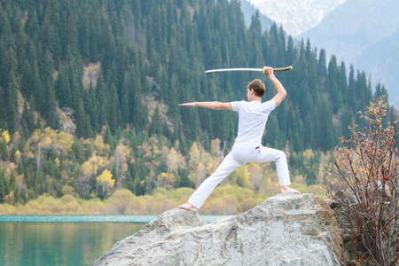 A man with a Japanese sword took up a fighting stance. Training in the mountains.の写真素材