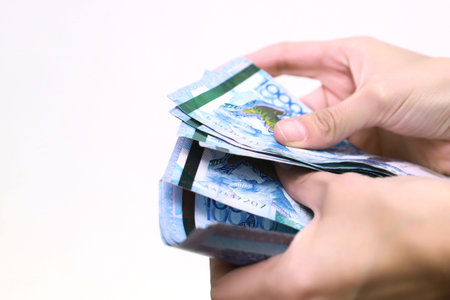 The women hand holds the national currency of Kazakhstan tenge.