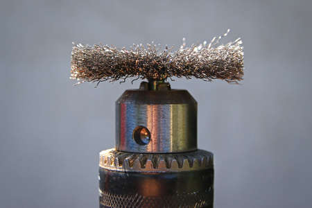 Metal nozzle brush for electric drill for brushing wood on gray background.の写真素材