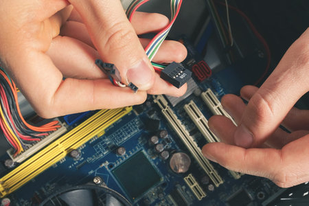 The repairer connects the wires in the computer. Repair and dismantling of computer equipment
