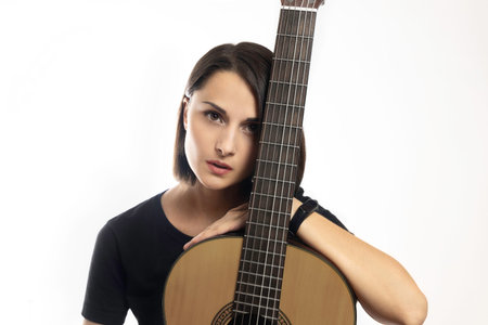 Portrait of young beautiful brunette with classical guitar on white background