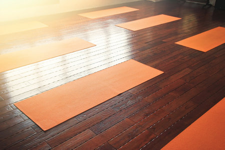 Orange yoga mats lie on the wooden floor in the yoga hallの写真素材