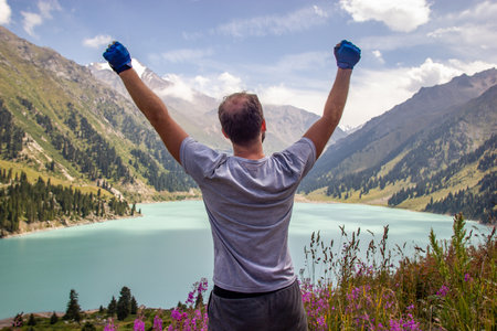 A man raised his hands to the sky against the backdrop of a Big Almaty Lake on summer day, amazing Kazakhstan natureの写真素材