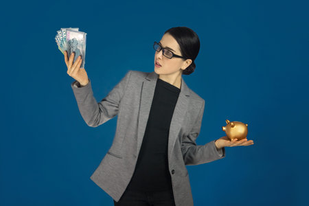 Woman in gray jacket with an Qazaqstan tenge and a money box in her handsの写真素材