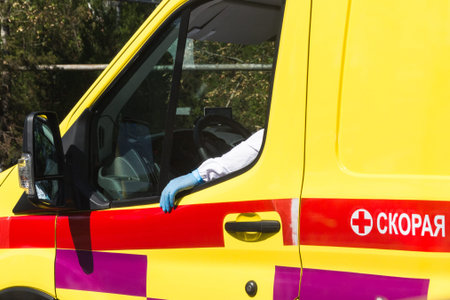 The hand of an ambulance driver in virus protection and a glove lies on the window of an ambulance...