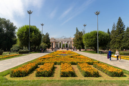 View of the central city Gorky park entrance. Square with a flower bed and walking people on a sunny summer day.のeditorial素材