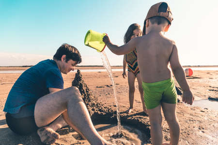 Young father playing with children on the beach. Lifestyle toned photoの写真素材